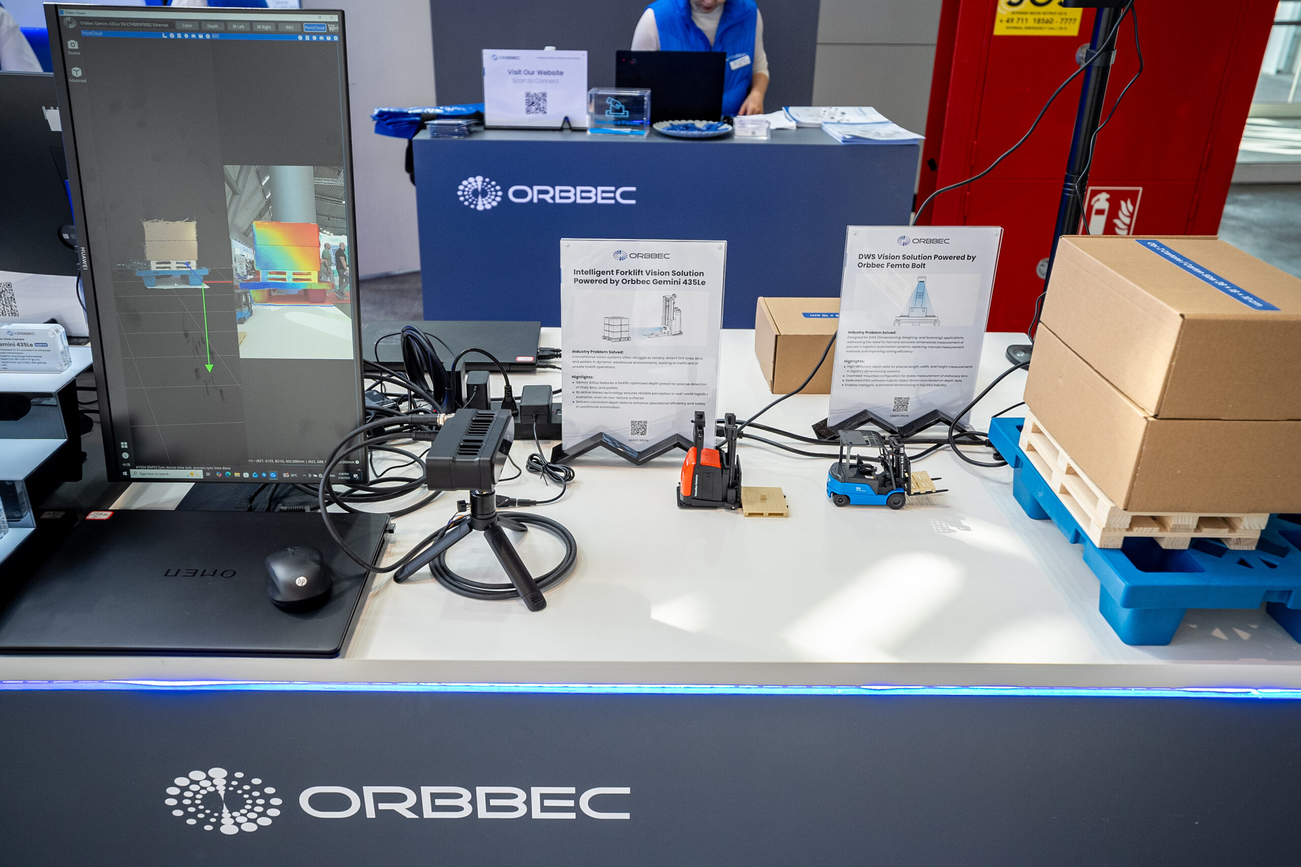 Orbbec LogiMAT 2026 booth demo table featuring Intelligent Forklift Vision Solution powered by Gemini 435Le and DWS Vision Solution powered by Femto Bolt with miniature forklift models and pallet