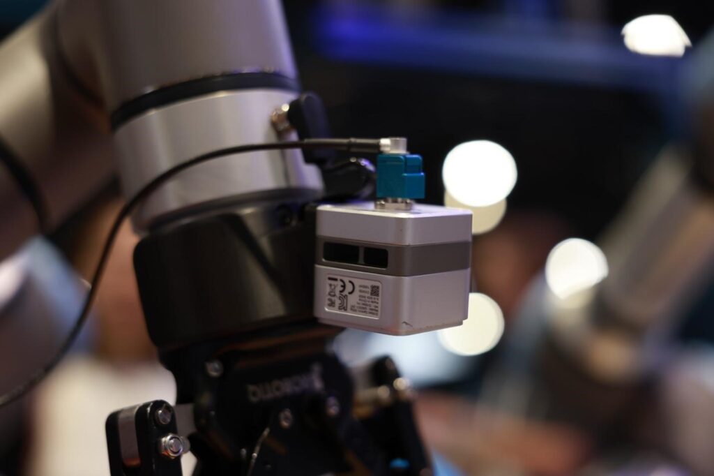 Close-up of Orbbec Gemini 305g stereo 3D camera mounted on Universal Robots cobot wrist joint for real-time depth and RGB data capture in Physical AI training
